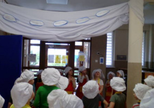 Dzieci w strojach kucharzy podczas podziwiania wystawy Rzeka mleka.